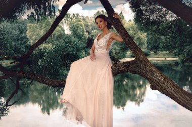 Gelin bir park Nehri yakınında bir ağaçta oturuyor