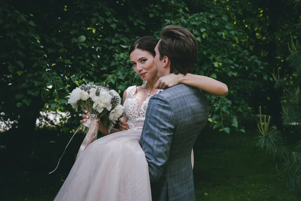 O noivo usa uma noiva nos braços — Fotografia de Stock