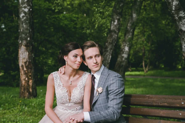 The bride and groom are sitting on a bench in a park near the lake — Stock Photo, Image