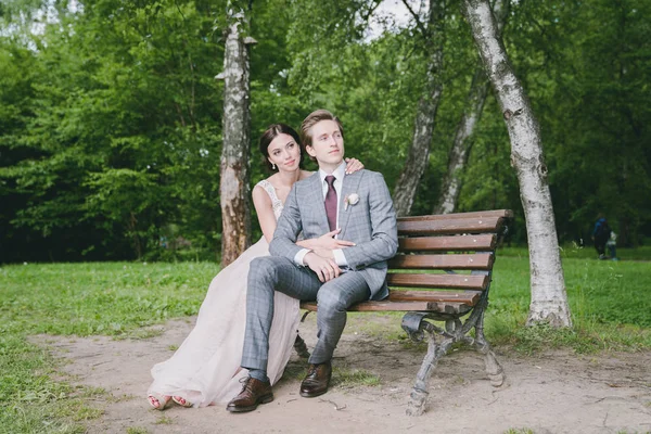 Dziewczyna i człowiek siedzi na ławce w parku w pobliżu jeziora — Zdjęcie stockowe