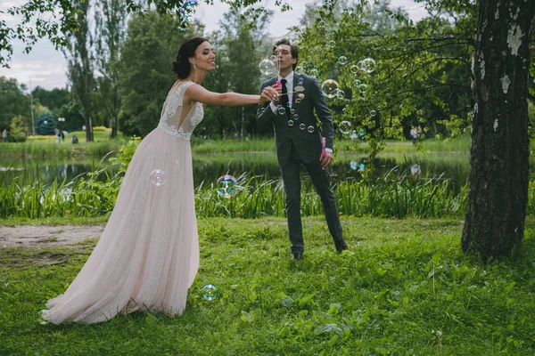 Дівчина і чоловік дме бульбашки в парку — стокове фото