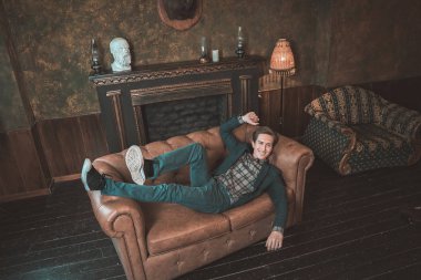 Şömine yakın bir deri kanepe üzerinde mutlu bir adam yatıyor