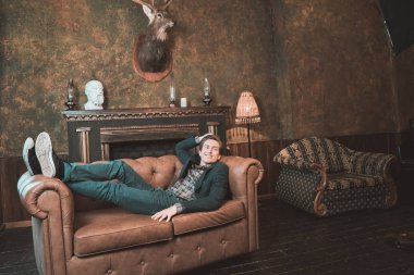 Şömine yakın bir deri kanepe üzerinde mutlu bir adam yatıyor