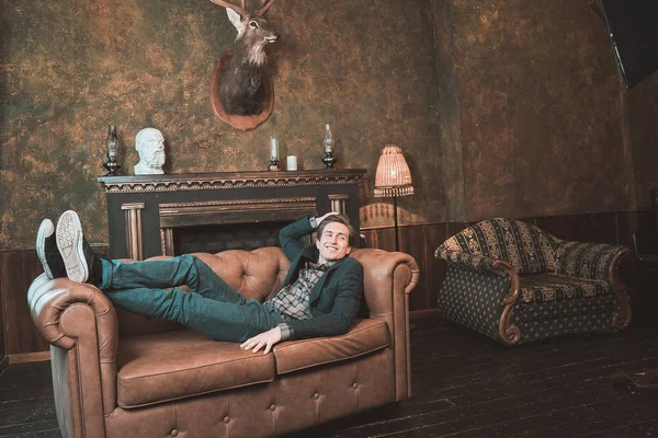 Şömine yakın bir deri kanepe üzerinde mutlu bir adam yatıyor