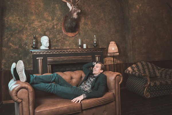 Şömine yakın bir deri kanepe üzerinde mutlu bir adam yatıyor