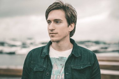 Kot pantolon giymiş bir adam bir Yat kulübünde bulutlu havalarda Nehri yakınında bir iskelede duran ve gülümseyen