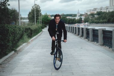 Bir adam bir parkta bulutlu havalarda setin bir bisiklet sürme