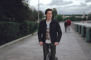 Bir adam bir parkta bulutlu havalarda setin bir bisiklet sürme