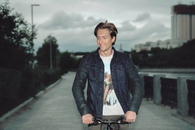 Bir adam bir parkta bulutlu havalarda setin bir bisiklet sürme