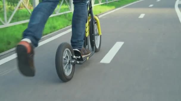 Een man rijdt op een scooter in het park — Stockvideo