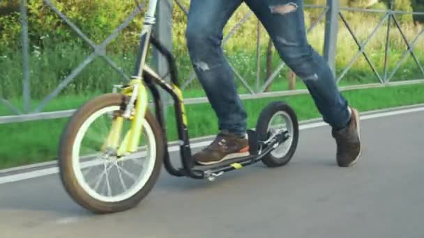 Een man rijdt op een scooter in het park — Stockvideo