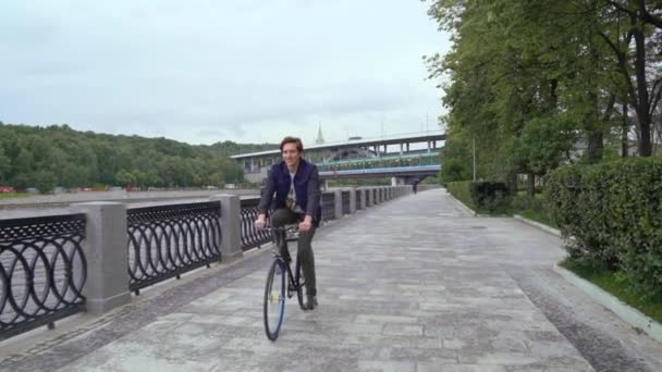 Muž jede na kole v parku na nábřeží — Stock video