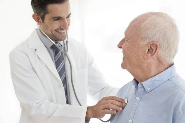 Médico Masculino Examinando Paciente Sênior Com Estetoscópio — Fotografia de Stock