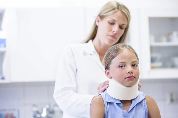 女医生向年轻女孩申请颈部支助 — 图库照片