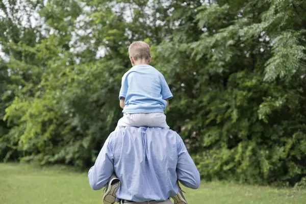 背面の肩の上の息子を運ぶ父 — ストック写真