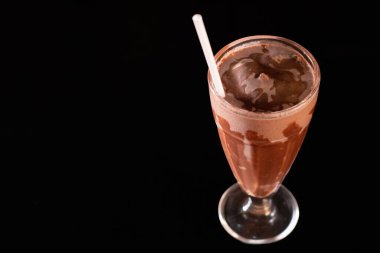 Siyah arka planda bardakta lezzetli bir milkshake.