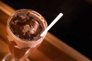 Ahşap arka planda bardakta lezzetli bir milkshake.