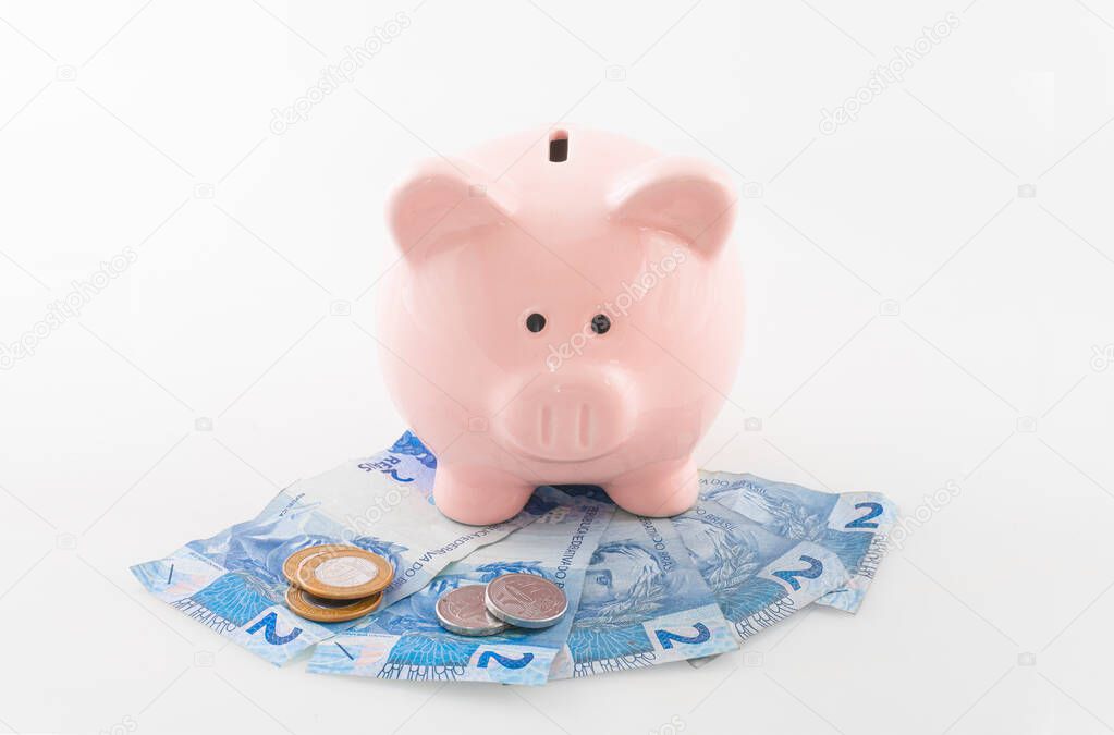 Pink piggy bank and brazilian currency (coin) isolated on a white background.