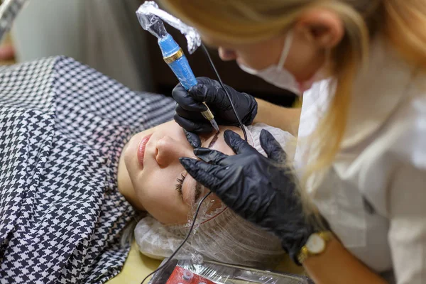 Микролезные брови работают в салоне красоты. Женщине тонировали брови. Полупостоянный макияж для бровей . — стоковое фото