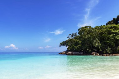 Altın sarı kum parlak güneşli bir günde mavi deniz kenarında ıssız bir sahilde.