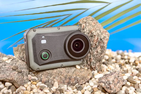 海砂と青い背景の背景と植物の葉に対して石の間でアクション カメラ — ストック写真