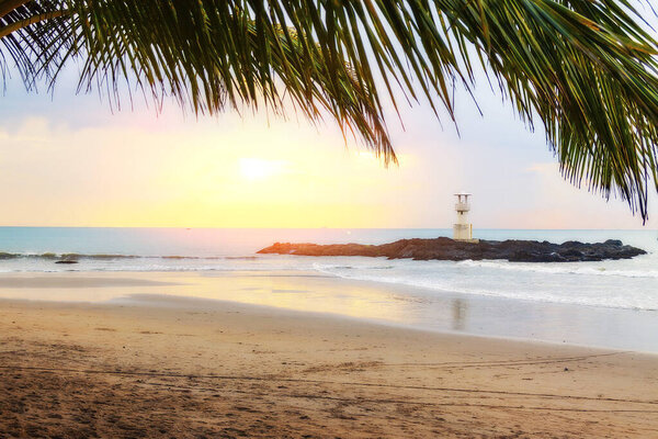 Sunset on the beach with palm trees overlooking the lighthouse.