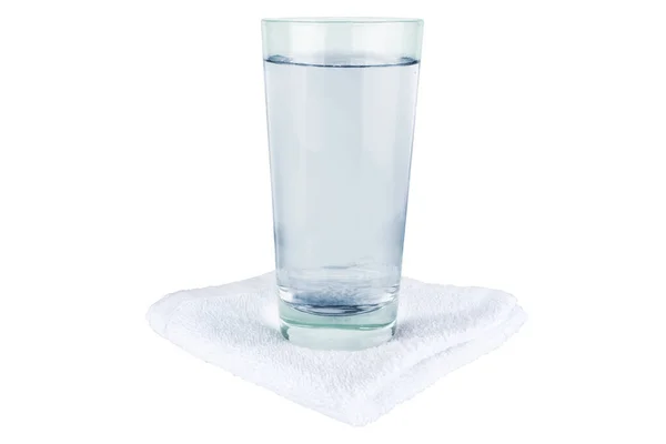 A glass of water stands on a towel. — Stock Photo, Image