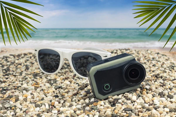 Sun goggles and action camera by the sea