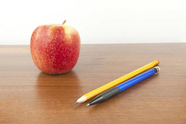 An apple with pencils is on the table, a white background