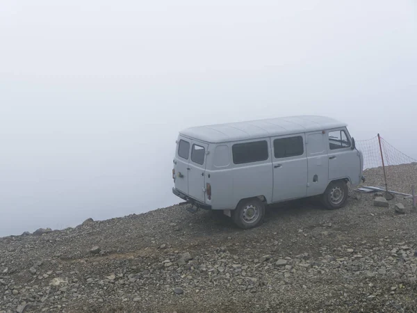 Car on the brink of an abyss in the fog of the clouds. Caucasus