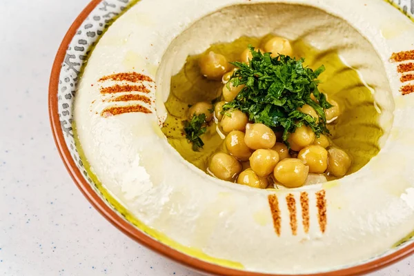 Arabic food Hummus with parsley in a traditional bowl.