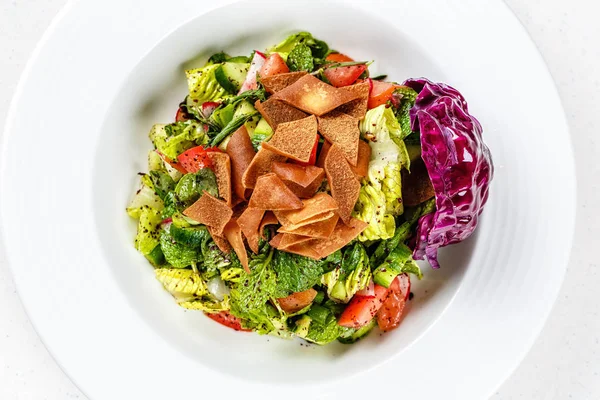 Fattoush ou salada de pão com croutons pita, legumes frescos e ervas, em prato branco na mesa de madeira com sumac, limão, molho de azeite, receita autêntica fácil e saudável — Fotografia de Stock