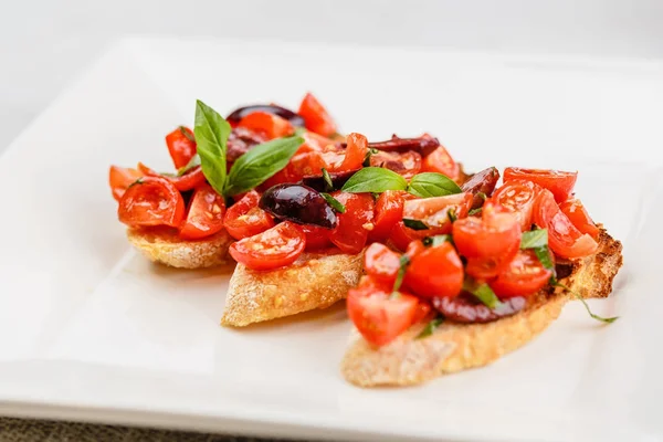 Итальянская брускетта с нарезанными помидорами, базиликом и оливками — стоковое фото