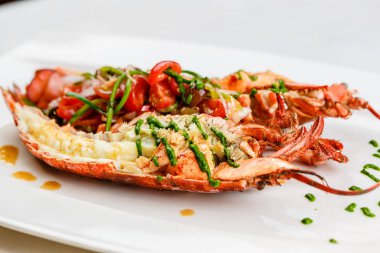 İtalyan mutfağı. Bütün ıstakoz pişmiş ve dilimlenmiş domates salatası ve beyaz tabakta sos ile yarım Served içinde