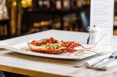 İtalyan mutfağı. Bütün ıstakoz pişmiş ve dilimlenmiş domates salatası ve beyaz tabakta sos ile yarım Served içinde