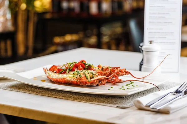 İtalyan mutfağı. Bütün ıstakoz pişmiş ve dilimlenmiş domates salatası ve beyaz tabakta sos ile yarım Served içinde