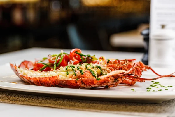 İtalyan mutfağı. Bütün ıstakoz pişmiş ve dilimlenmiş domates salatası ve beyaz tabakta sos ile yarım Served içinde
