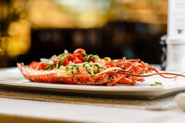 Italiaanse keuken. Hele kreeft gebakken en gesneden in halve opgediend met tomatensalade en saus op witte plaat — Stockfoto