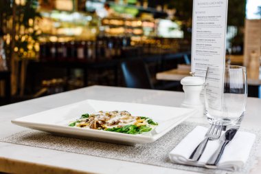 Taze kavrulmuş mantar ve kremsi parmesan peynir soslu ıspanak üzerinde beyaz plaka ile dekore edilmiş İtalyan Mantısı.