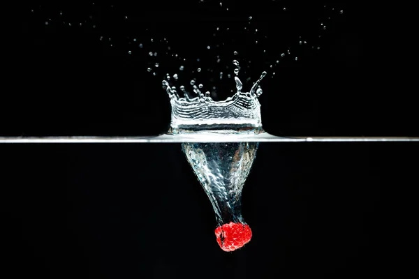 Himbeere fällt mit dickem Spritzer tief unter Wasser. — Stockfoto