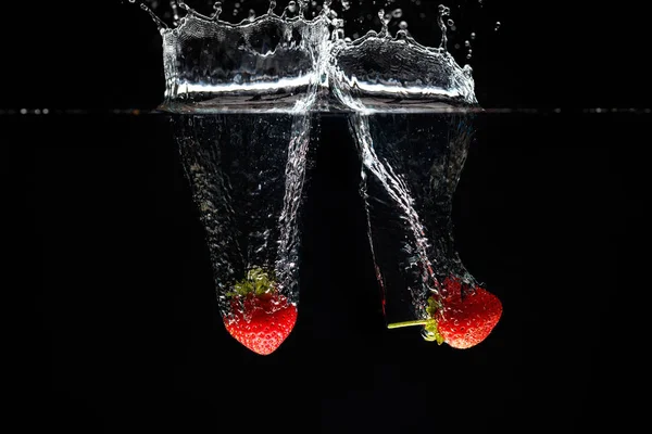 Due fragole che schizzano in acqua — Foto Stock