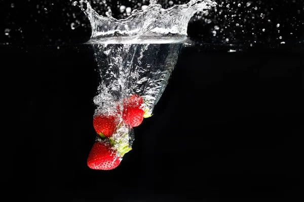 Drei Erdbeeren, die ins Wasser spritzen — Stockfoto