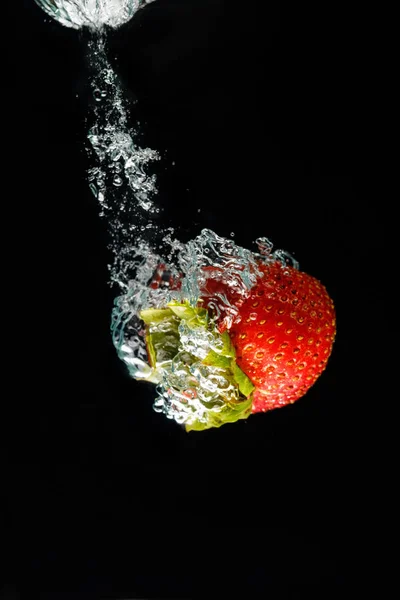 Eine Erdbeere, die ins Wasser spritzt — Stockfoto