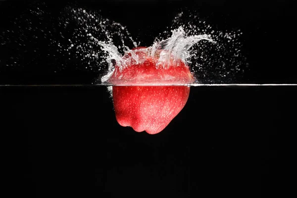 Ένα μήλο πέφτει βαθιά κάτω από το νερό με έναν μεγάλο παφλασμό. — Φωτογραφία Αρχείου
