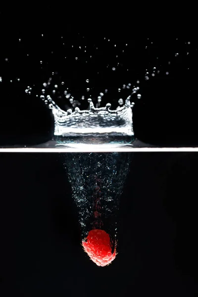 Δύο raspberrys πέφτει βαθιά κάτω από το νερό με έναν μεγάλο παφλασμό. — Φωτογραφία Αρχείου