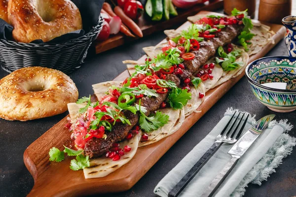Tahta servis tahtasının üzerinde kebap ve arap ekmeği.
