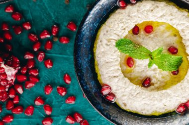 Sebze ve tohumlarla çevrili kasede humus var.