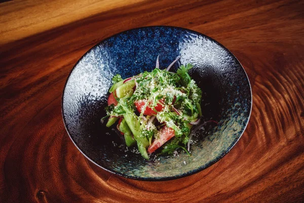 Salada verde servida em tigela escura com fundo de madeira — Fotografia de Stock