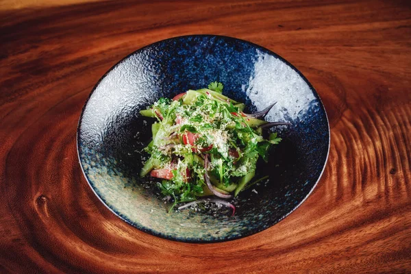 Salada verde servida em tigela escura com fundo de madeira — Fotografia de Stock