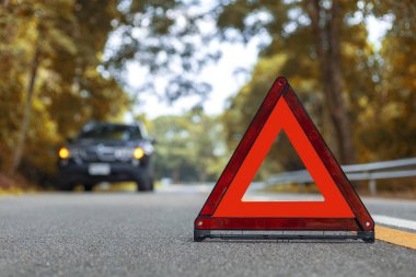Siyah araba yolda kaza yapmış. Kırmızı üçgen, kırmızı acil durum işareti, kırmızı acil durum sembolü ve siyah araba dur ve yola park et..